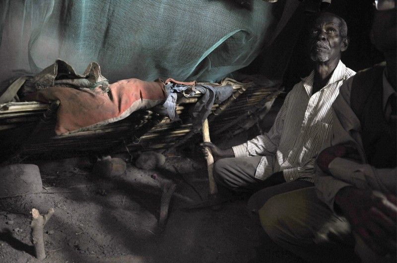 2) 76-летний Мабула сидит на корточках в спальне с земляным полом, возле могилы своей внучки, пятилетней Мариам Эммануэль, маленькой альбиноски, которая была убита и расчленена в соседней комнате в феврале 2008 года. Девочку похоронили прямо в хижине, чтобы охотники за частями тел альбиносов не растащили ее кости. Снимок сделан 25 января 2009 года в одной из деревень близ Мванзе. (TONY KARUMBA/AFP/Getty Images)