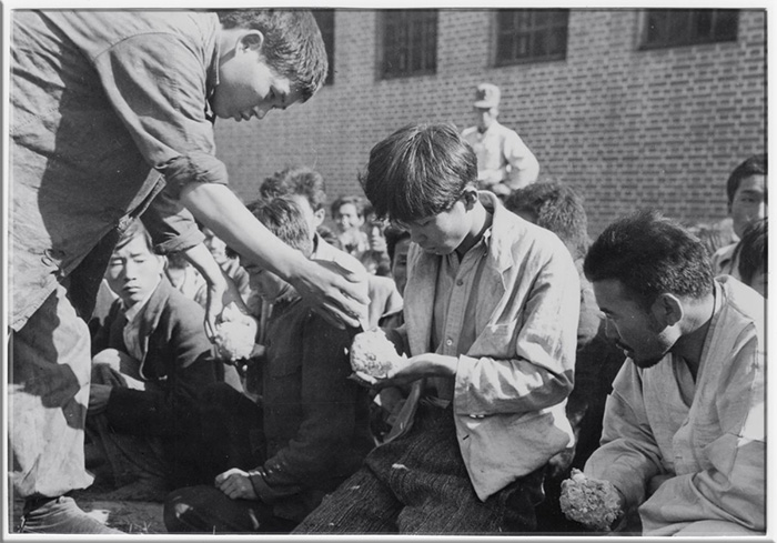 На этом снимке Красного Креста заключённые получают рисовые шарики во время Корейской войны. 